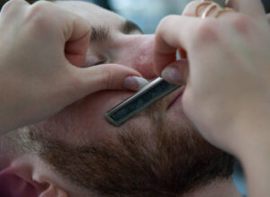 Barber uses straight razor to shave man's beard